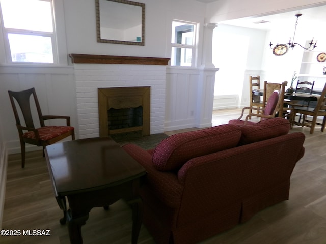 living room with a brick fireplace, hardwood / wood-style flooring, and a chandelier