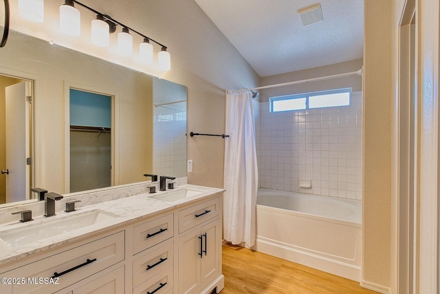 bathroom with visible vents, wood finished floors, shower / bath combo with shower curtain, and a sink