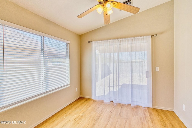 empty room featuring a ceiling fan, lofted ceiling, wood finished floors, and baseboards