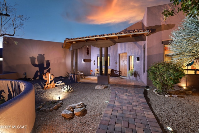 back house at dusk featuring a patio