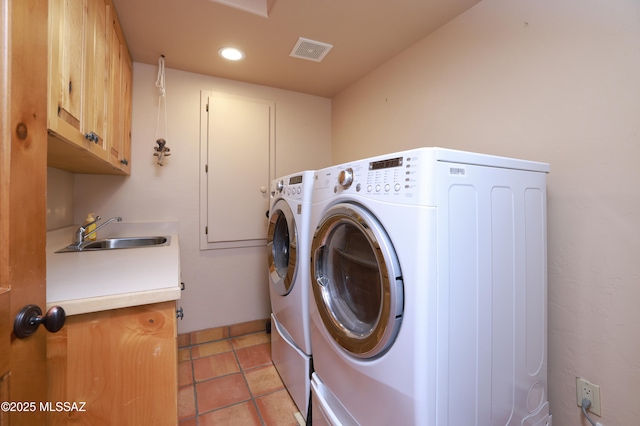 clothes washing area featuring sink, light tile patterned floors, washer and clothes dryer, and cabinets