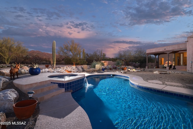 pool at dusk featuring an in ground hot tub and a patio area