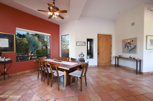 tiled dining area featuring ceiling fan and a high ceiling