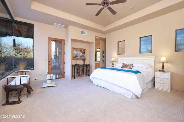 bedroom with a raised ceiling, carpet floors, and multiple windows