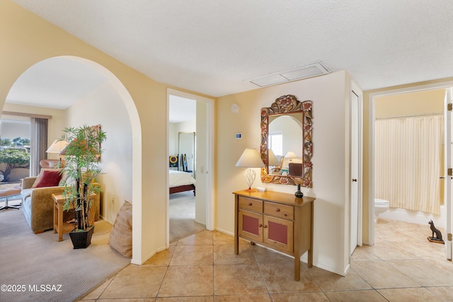 hallway featuring a healthy amount of sunlight, light tile patterned floors, and a textured ceiling