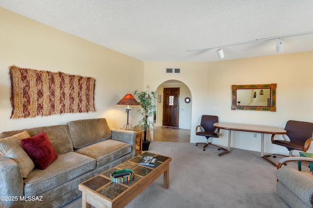 living room with light colored carpet, rail lighting, and a textured ceiling