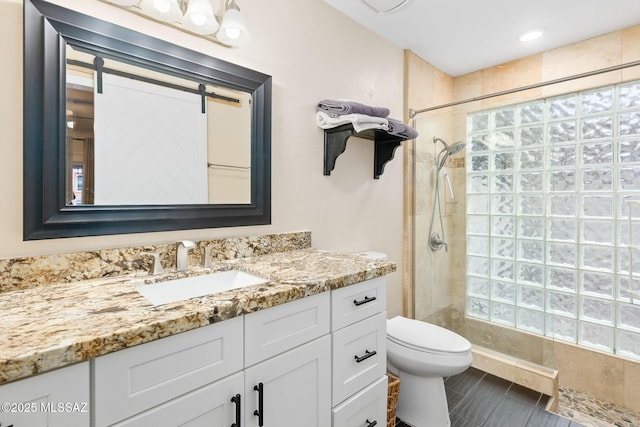 bathroom with tiled shower, vanity, and toilet