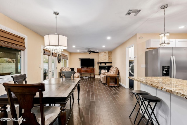 dining room with french doors, a fireplace, dark hardwood / wood-style flooring, ceiling fan, and washer / clothes dryer