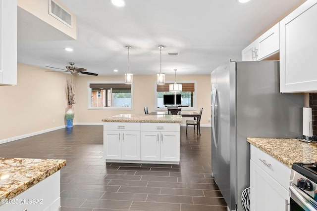 kitchen with pendant lighting, stainless steel stove, white cabinets, ceiling fan, and light stone counters