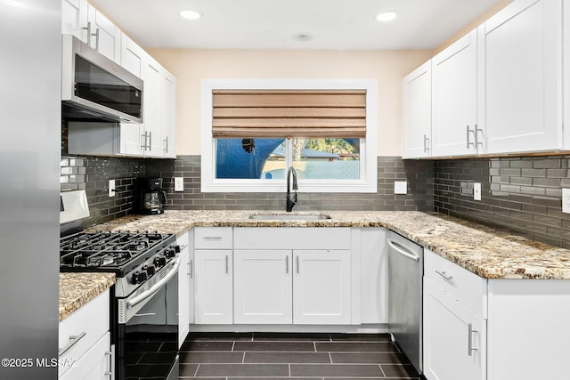 kitchen with white cabinetry, sink, light stone counters, and appliances with stainless steel finishes