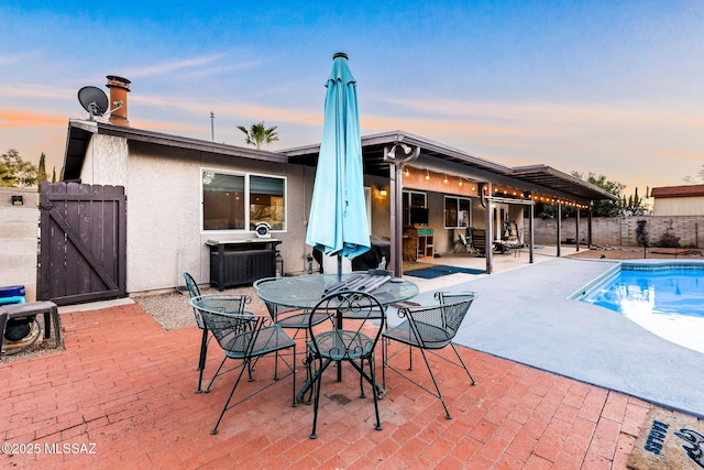 pool at dusk featuring a patio area