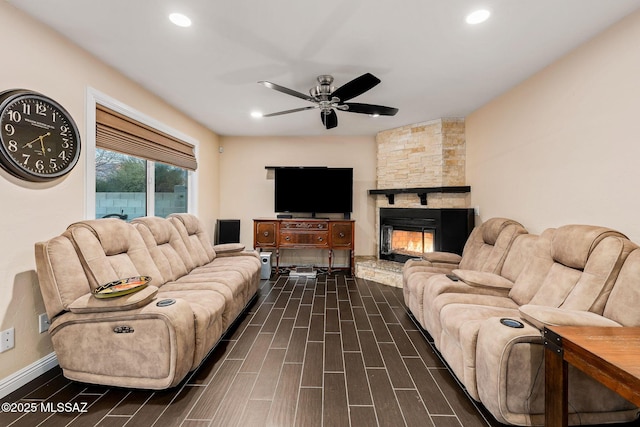 living room featuring a stone fireplace and ceiling fan