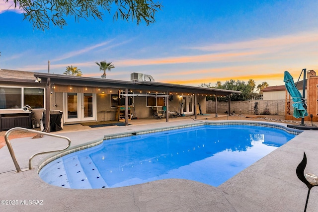 pool at dusk with french doors, a patio area, and central air condition unit