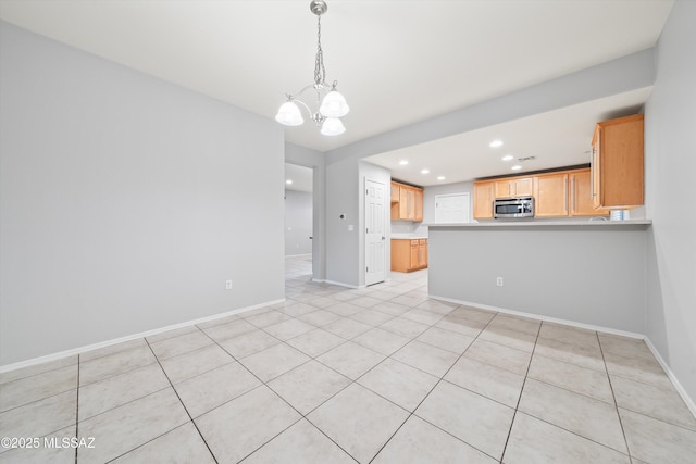 interior space featuring pendant lighting, a notable chandelier, light brown cabinetry, and kitchen peninsula