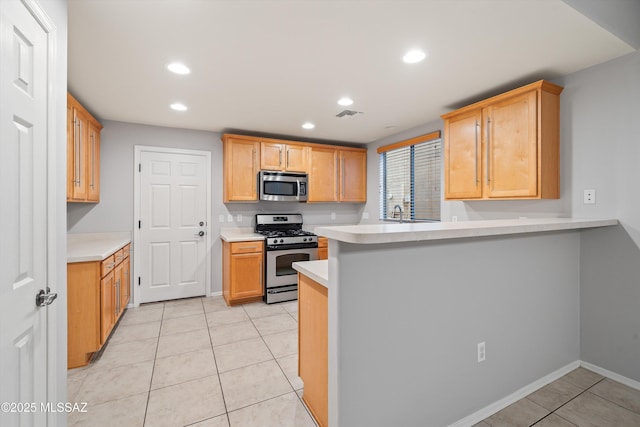kitchen with stainless steel appliances, light tile patterned floors, light brown cabinets, and kitchen peninsula