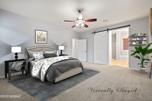carpeted bedroom with a barn door, ceiling fan, and ensuite bathroom