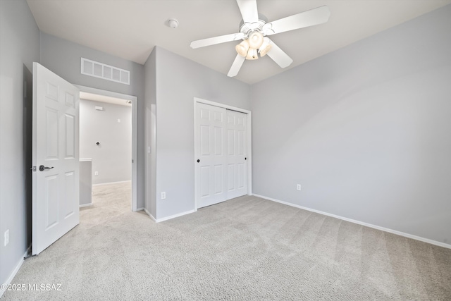 unfurnished bedroom with ceiling fan, light colored carpet, and a closet