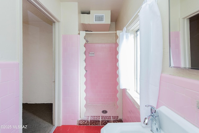 bathroom featuring tile walls, sink, a wealth of natural light, and a tub