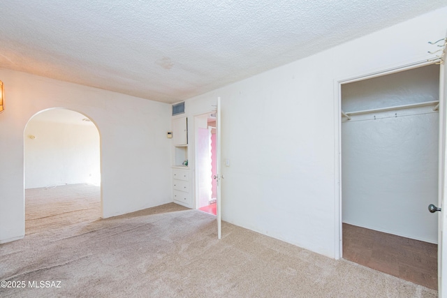 unfurnished bedroom with a closet, light carpet, and a textured ceiling