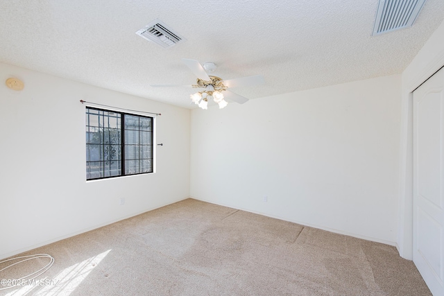 carpeted spare room with ceiling fan and a textured ceiling