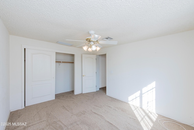 unfurnished bedroom with ceiling fan, light colored carpet, a closet, and a textured ceiling