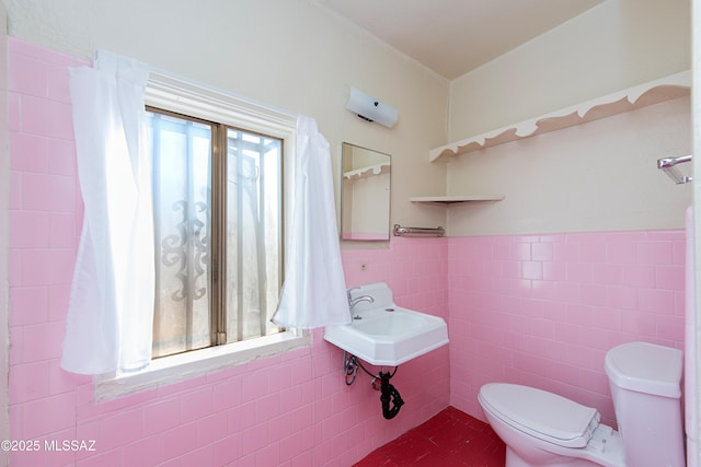 bathroom with sink, tile walls, and toilet