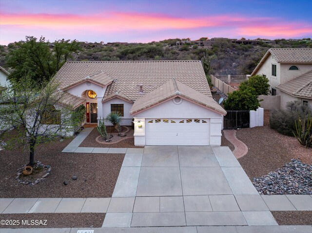 view of front facade with an attached garage, a tile roof, a gate, and concrete driveway