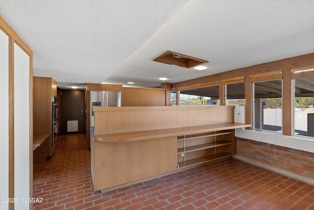 interior space featuring appliances with stainless steel finishes, kitchen peninsula, and a textured ceiling