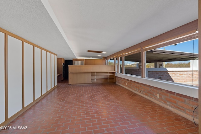 interior space featuring brick wall and a textured ceiling