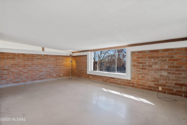 unfurnished room with brick wall, concrete floors, and a textured ceiling