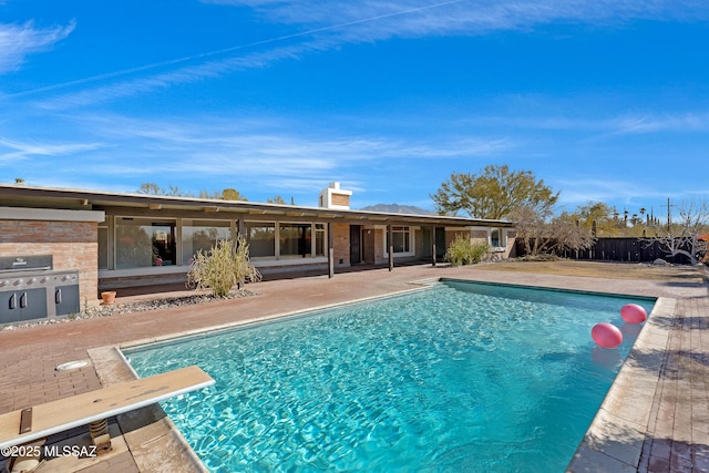 view of swimming pool featuring area for grilling, a patio, and a diving board