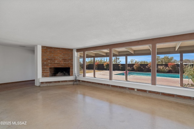 unfurnished living room with plenty of natural light, a fireplace, and a textured ceiling