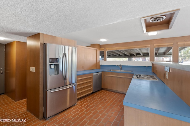 kitchen featuring light brown cabinetry, sink, stainless steel appliances, and a textured ceiling