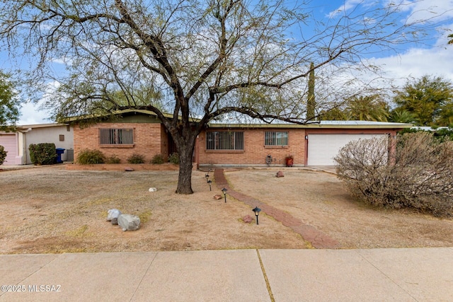 single story home with brick siding, central AC unit, and an attached garage