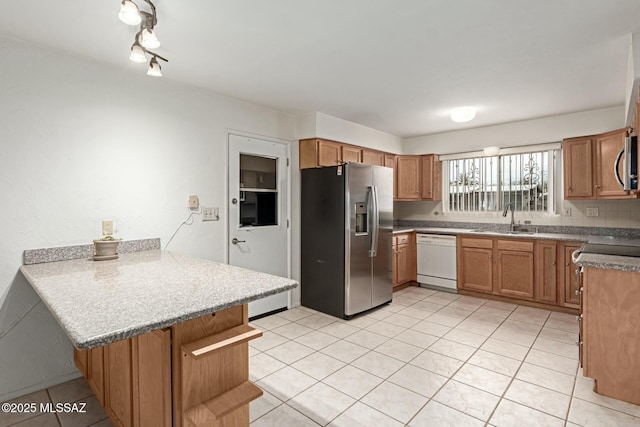 kitchen featuring a sink, stainless steel appliances, a peninsula, and brown cabinetry