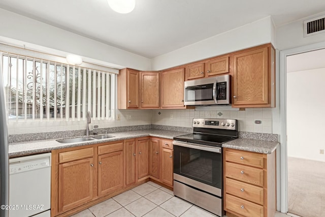 kitchen featuring visible vents, light countertops, decorative backsplash, stainless steel appliances, and a sink