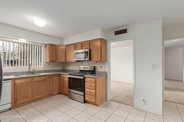 kitchen with visible vents, a sink, decorative backsplash, stainless steel appliances, and light colored carpet