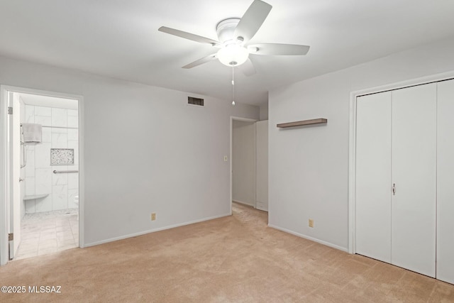 unfurnished bedroom with ceiling fan, a closet, connected bathroom, and light carpet