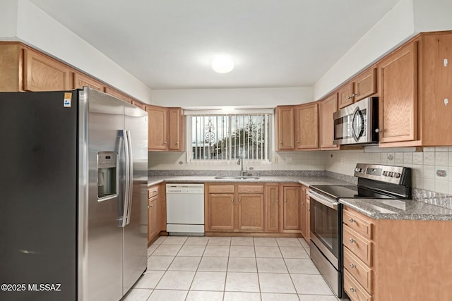 kitchen featuring light tile patterned floors, brown cabinetry, a sink, appliances with stainless steel finishes, and tasteful backsplash