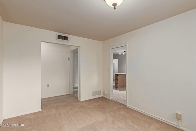 spare room featuring visible vents and light carpet