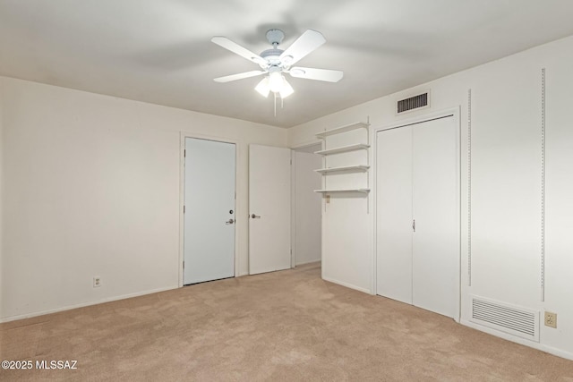 unfurnished bedroom featuring multiple closets, light carpet, and ceiling fan