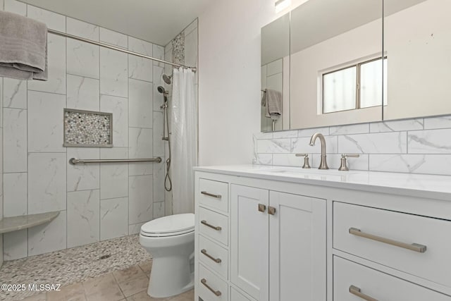 bathroom featuring backsplash, toilet, vanity, and a tile shower
