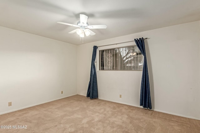 carpeted spare room featuring a ceiling fan and baseboards