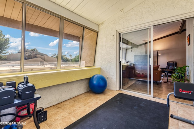 exercise room with light tile patterned flooring and vaulted ceiling