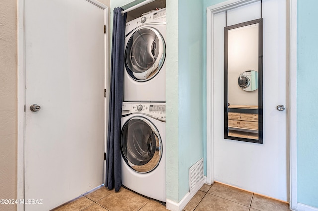 laundry area with light tile patterned flooring and stacked washer and clothes dryer