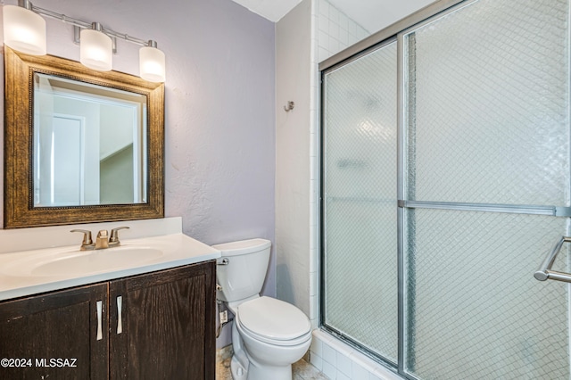 bathroom with vanity, a shower with shower door, and toilet