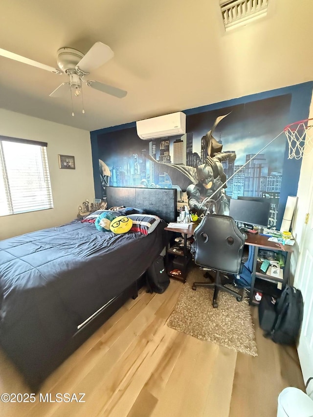 bedroom with hardwood / wood-style floors, a wall mounted AC, and ceiling fan