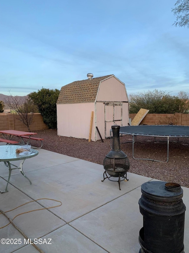 view of patio featuring a trampoline, a fire pit, and a storage unit