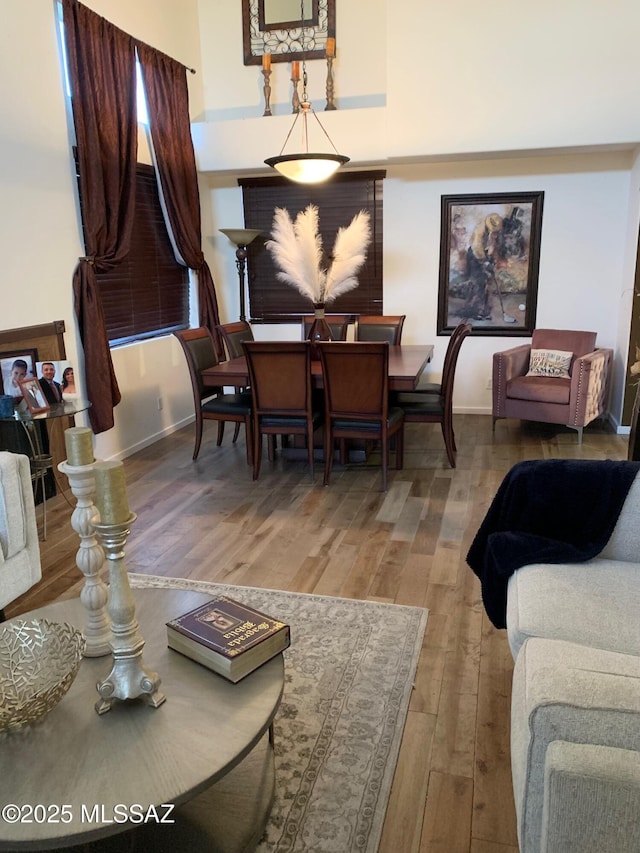 dining space with wood-type flooring and a high ceiling