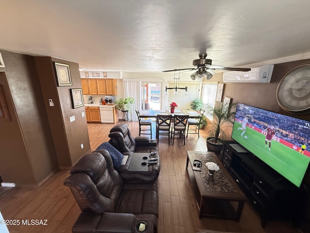 living room featuring hardwood / wood-style floors, a wall mounted AC, and ceiling fan